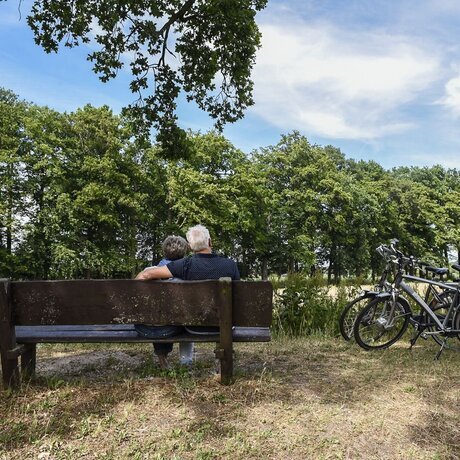 stel-man-vrouw-bos-bank-bankje-bomen-gras-fietsen.jpg